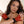 Load image into Gallery viewer, A nude brunette woman poses in front of a blank background with her arms crossed over her chest. She wears the Pia Frilled Gloves by Syren latex in red with black trim. The gloves are fingerless and have a black ruffle at the wrists.
