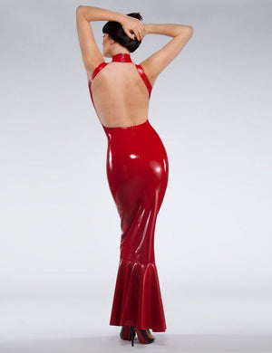 A brunette woman poses in front of a grey background, facing away from the camera and holding her hair up. She wears the red fishtail latex gown from Syren Latex, which has an open back.