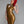Load image into Gallery viewer, A woman with bright red hair poses in front of a grey backdrop wearing the Tami Latex Dress by Syren Latex in Pearl Gold. The sleeveless dress has a small collar and three teardrop-shaped cut outs on the chest. The hem ends at her knees.
