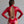 Load image into Gallery viewer, A brunette woman poses in front of a grey backdrop, facing away from the camera. She wears the Nadia Latex Bodysuit in red by Syren Latex. There is a large cutout on the back of the suit with corset-style lacing,  exposing most of her back. 
