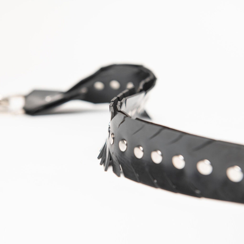 Close up detailed shot of rubber strap with studs and a feathered edge on a white background