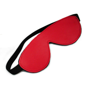 The Padded Leather Blindfold in red is shown against a blank background. The blindfold is made of red leather and has a thick black elastic strap.