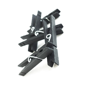 Five black clothespins from the Gripper Clothespins 30 Pack are displayed against a blank background, piled on top of each other.