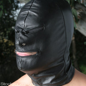 A close-up of a man wearing the black leather Jack the Zipper Bondage Leather Hood is shown. The hood completely covers his face, head, and neck. The hood has nostril holes and zippers over each eye and one over the mouth, which is open.