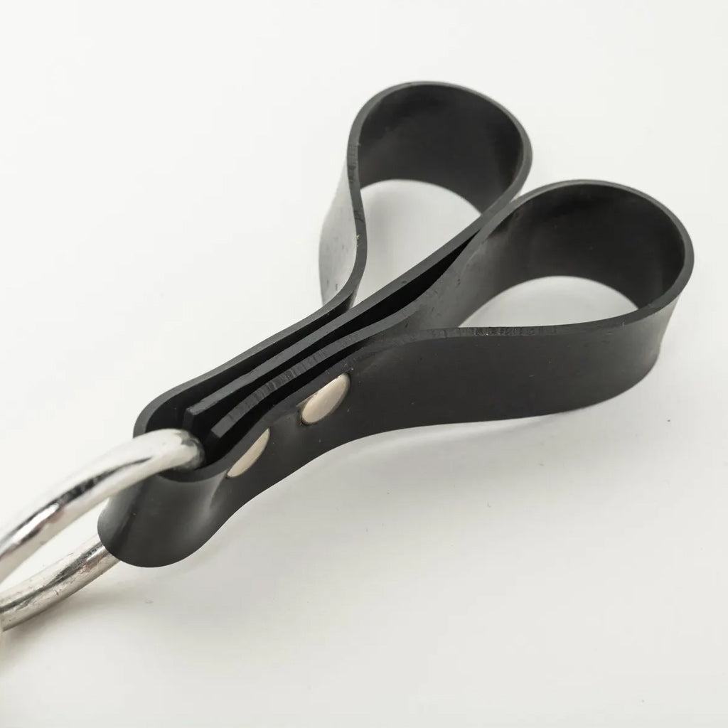 Close up of black rubber loops with a metal ring on a white background