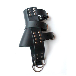 One Boot Suspension Cuff is shown against a blank background. The front of the cuff has a flat piece of black leather on one side, flanked by verticle leather strips with D-rings on the end. The back of the cuff has three horizontal straps.