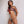 Load image into Gallery viewer, A nude woman with an undercut stands against a blank wall with her hands behind her back. The Steel Vaginal Hook/Hanger is inserted into her vagina and held upright by a red rope, which is tied to the purple rope that binds her chest.
