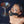 Load image into Gallery viewer, A nude brunette woman wearing the Scott Paul Humiliator Gag with the Serving Tray Attachment kneels on the floor, looking up at the camera. A metal martini glass sits on the tray.
