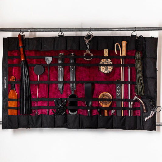 A wide view of the KinkBag spread open  to show its full width. There are an assortment of BDSM toys in the pouches and straps. 
