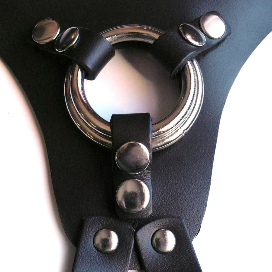 A close-up of the center of the black leather La Strap On harness, showing the two different-sized silver metal O-rings that it comes with.