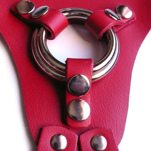 A close-up of the center of the red leather La Strap On harness, showing the two different-sized silver metal O-rings that it comes with.