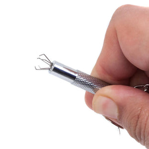 Someone holds an Extreme Talon Nipple Clamp against a blank background, showing a close-up of the exposed claws. The claws, made of five small, metal claws that branch outwards and are bent inwards at a 90-degree angle, emerge from the tip of the clamp.