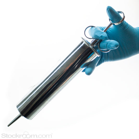 A hand in a blue rubber glove is shown holding the classic clyster enema syringe Against a white background.