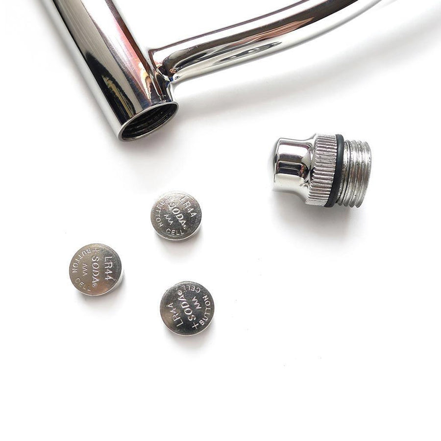 A close-up of the hook of the Trailer Hitch Power Train plug is displayed against a blank background. The cap at the end of the rod is open, with three small batteries near it.