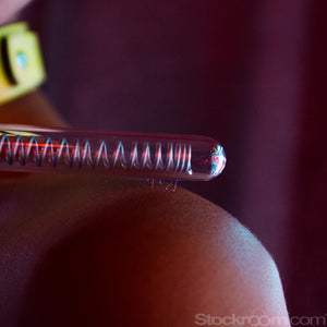 A close-up of a woman’s shoulder with the KinkLab Coiled Probe Neon Wand® Electroplay Attachment hovering over it is shown. There are tiny bolts of electricity coming from the probe and hitting her shoulder.