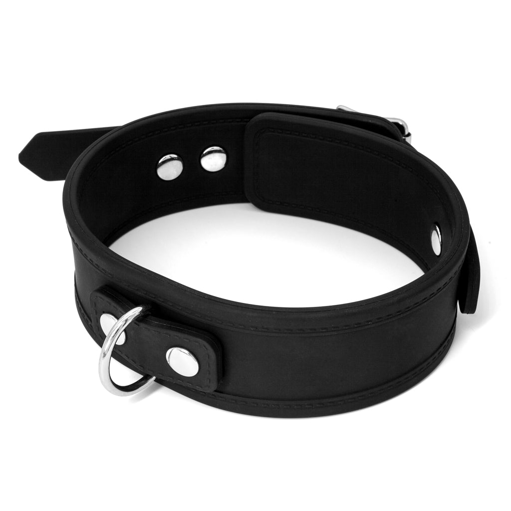 The Silicone Locking Collar is displayed against a blank background. It is made of a relatively wide piece of matte black silicone with faux stitching along the borders. It has a metal D-ring at the front and decorative metal rivets.