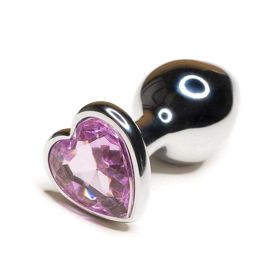 The Baby Pink Jewel Stainless Steel Heart Butt Plug is shown against a blank background. The plug is shiny silver and is tapered with a thin neck and wide base. The base is heart-shaped with a light pink heart-shaped gem embedded in it.