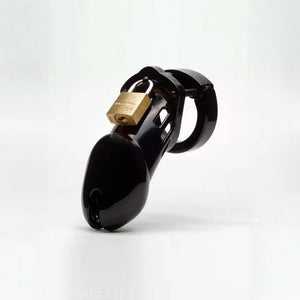 The CB-6000 Male Chastity Device in black is shown against a blank background. The chastity cage is the shape of a flaccid penis and is black and shiny, with a brass padlock on top. There is a rectangular slit at the tip of the cage.