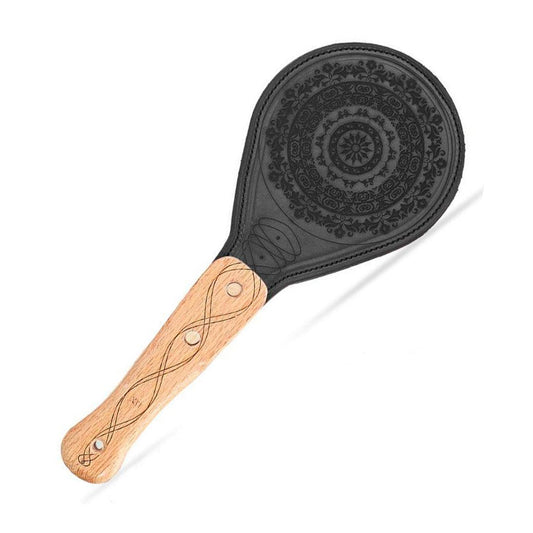 The LVX Floral Leather Paddle is displayed against a blank background. The handle of the paddle is a light colored wood with a darker swirling design. The upper portion of the paddle is black leather decorated with an intricate floral design.