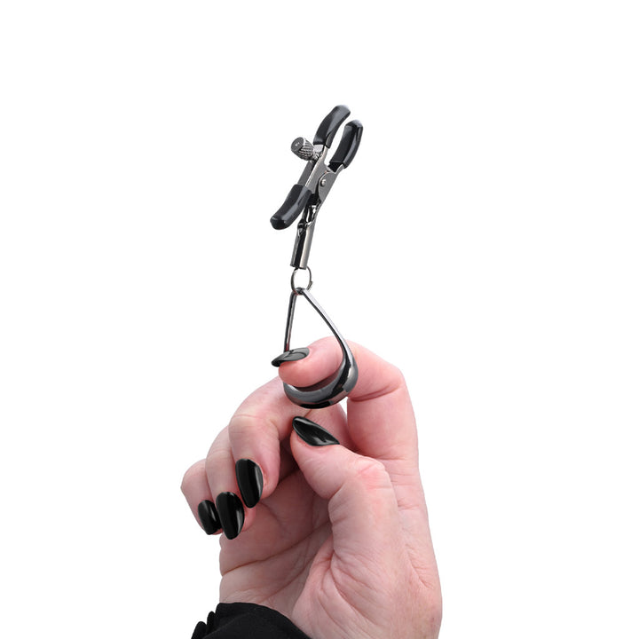 A product shot of the Velvet Noir Tuggable Nipple Clamps on a white background, with a woman's finger through the metal loop, as if pulling on it. 