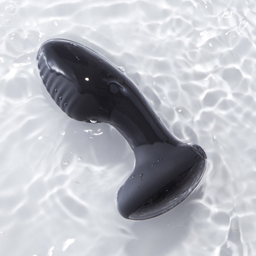 Black model of the Frenzy pressure sensitive butt plug floating in water. 