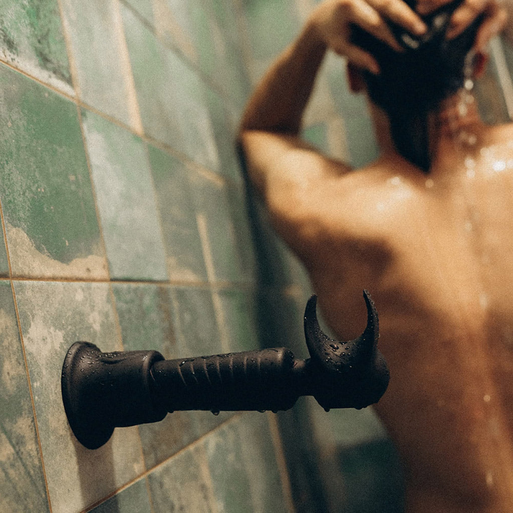 A photograph of the man.wan Vibrator attached to a shower wall with a suction cup. 
