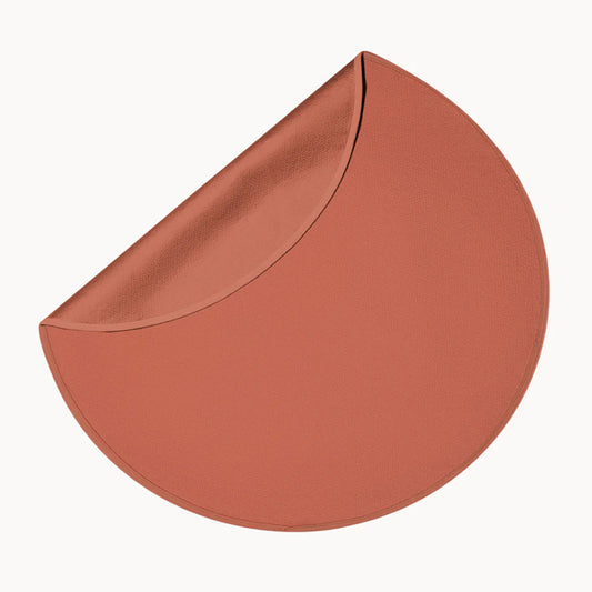 Picture of the Dame Sex Blanket, a copper-brown color in a circular shape. One edge is folded over to show the surface that goes against the mattress.