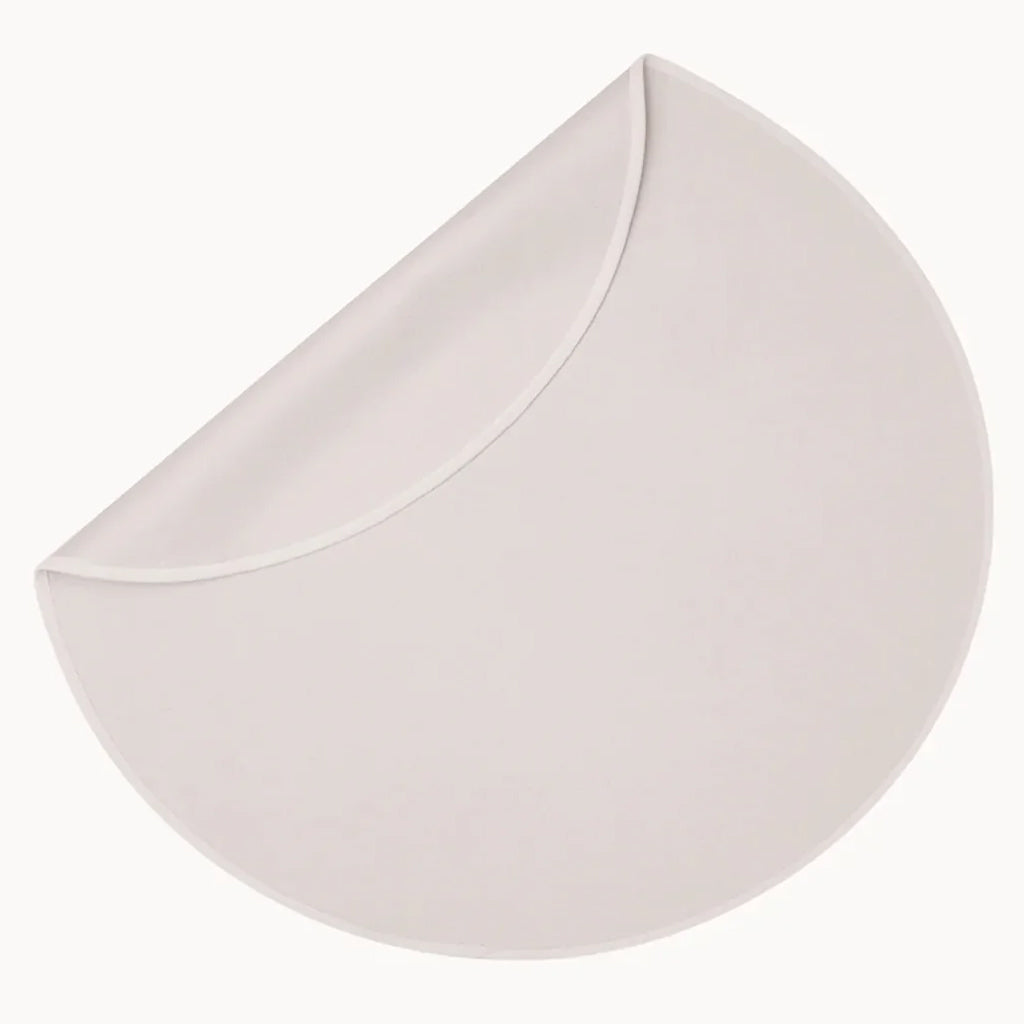 Picture of the Dame Sex Blanket, an oat color in a circular shape. One edge is folded over to show the surface that goes against the mattress.