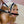 Load image into Gallery viewer, A close-up of a blonde woman wearing the Rubber Bit Trainer Gag is shown. The gag is a long, black silicone bit connected to leather chin and head straps by two large metal O-rings on the sides.

