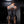 Load image into Gallery viewer, A man wearing boots is shown from behind, kneeling on a chair in a room painted black. He wears the lace-up black leather arm binder.
