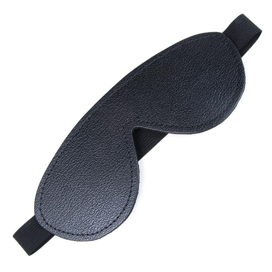 The black Fleece-Lined Leather Blindfold is shown against a blank background. It is made of black leather and shaped like goggles with a thick, black elastic strap.