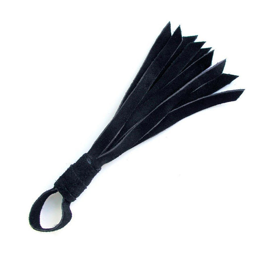 The black Teeny Weeny Leather Flogger from The Stockroom is shown against a blank background. It is a mini flogger made of black suede with a tiny handle and loop at the end.