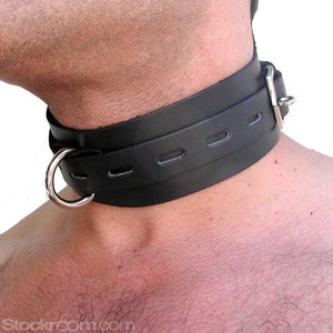 A close-up of a man's neck in the BDSM Black Leather Collar with Locking Buckle is shown. The collar is made of a wide strip of black leather with a smaller notched strip in the center. It has a metal D-ring in the center.