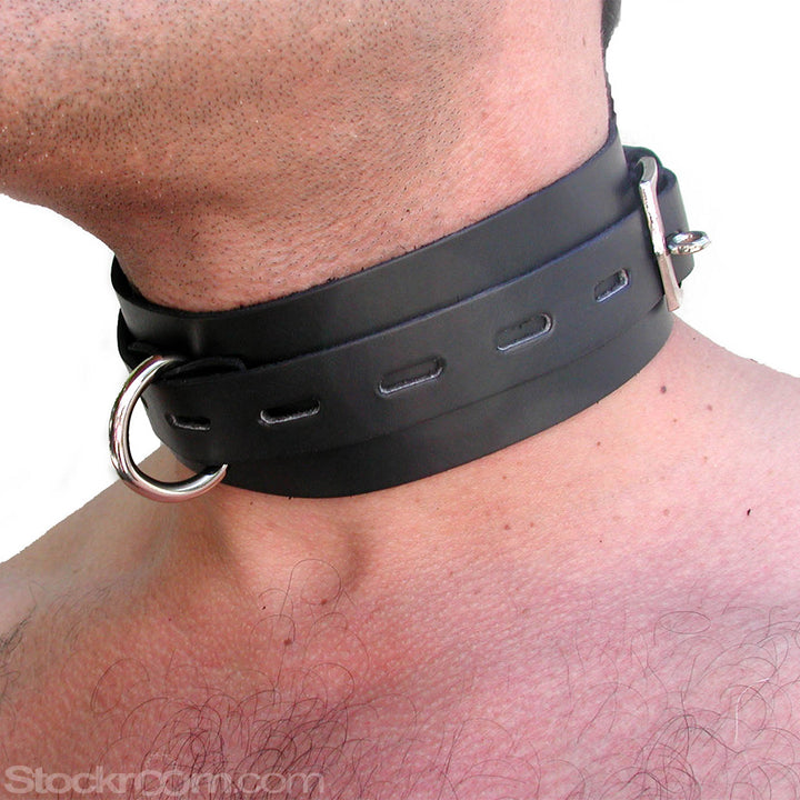 A close-up of a man's neck in the BDSM Black Leather Collar with Locking Buckle is shown. The collar is made of a wide strip of black leather with a smaller notched strip in the center. It has a metal D-ring in the center.