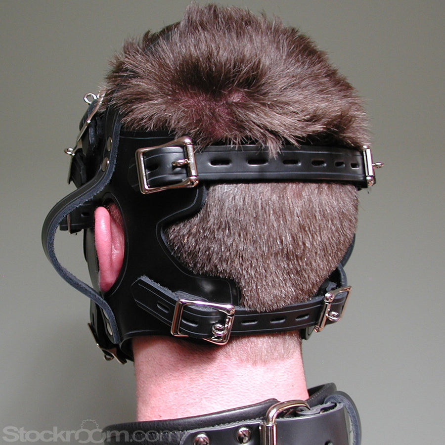 A close-up of the back of a man's head in the Inescapable Head Harness is shown in front of a grey background. The black leather harness goes around the sides of his head and has loops near the ears. It also has an attached blindfold.