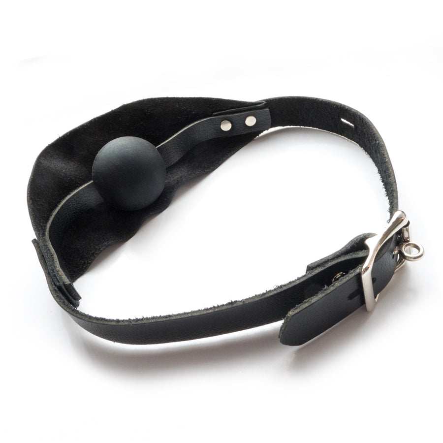 The Over The Mouth Gag With A Silicone Ball is shown from the back against a blank background. Behind the piece of leather is a black silicone ball gag. The strap is secured with a silver lockable buckle.