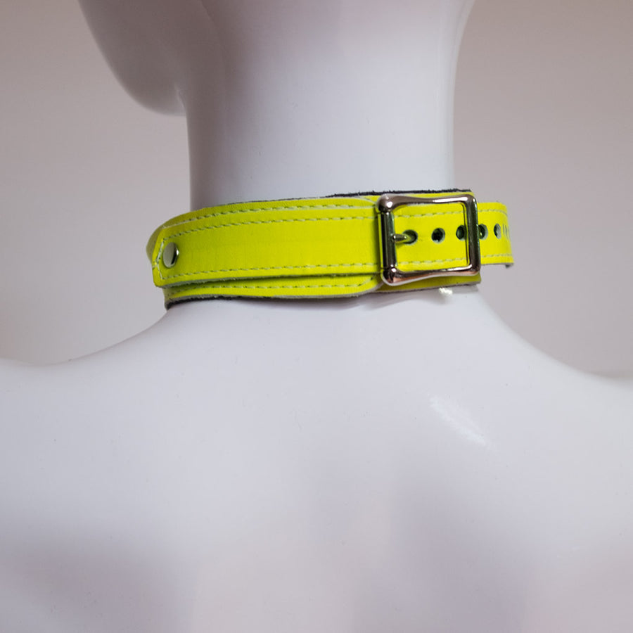A close-up of the back of the neck of a mannequin wearing the yellow Neon Angel Bust Harness is shown. The collar of the harness closes with a silver buckle.