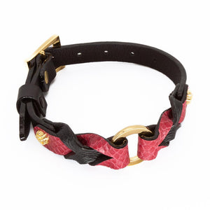 The Melanie Rose Designs x The Stockroom Collar, made of red and black leather braided together with a gold O-ring in the center, is displayed against a blank background.