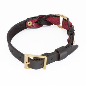 The Melanie Rose Designs x The Stockroom Collar, made of red and black leather braided together with a gold O-ring in the center, is displayed against a blank background.