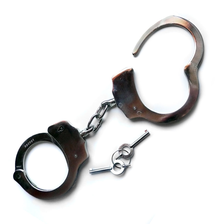 The silver Kinklab Double-Lock Police-Style Handcuffs are displayed against a blank background along with their keys. They resemble basic police cuffs with a short connecting chain.