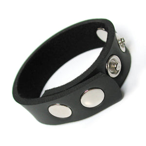 The black KinkLab 5-Snap Neoprene Cock Ring, made of a thin strip of neoprene with five snap closures on it, is displayed against a blank background.