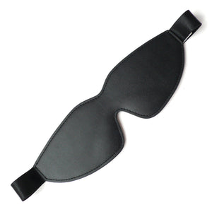 The black, faux-leather Kinklab Padded Blindfold is displayed against a blank background. It has a black elastic strap with a satin finish.