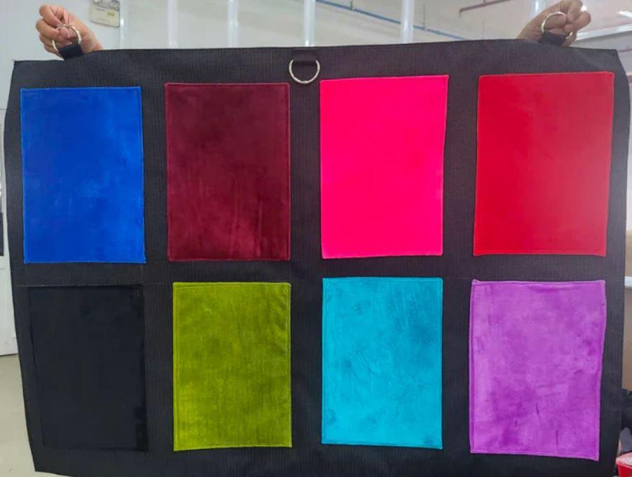 A sample cloth held up, showing eight interior colors available for the KinkBag.