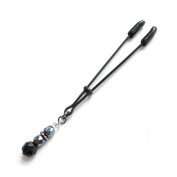 The Beaded Clit Clamp is displayed against a blank background. It is a black adjustable tweezer-style clamp with four decorative black and white beads dangling from the bottom.