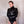 Load image into Gallery viewer, A man standing in front of a white wall is shown wearing the black Rubber BDSM Straitjacket. The jacket completely covers his arms, torso, and neck. The sleeves are sealed under his hands, and his arms are crossed over his chest.
