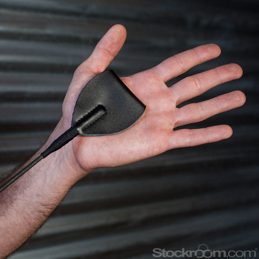 A closeup of the man’s palm with the leather end of the Black Leather Wide End Riding Crop resting in it.