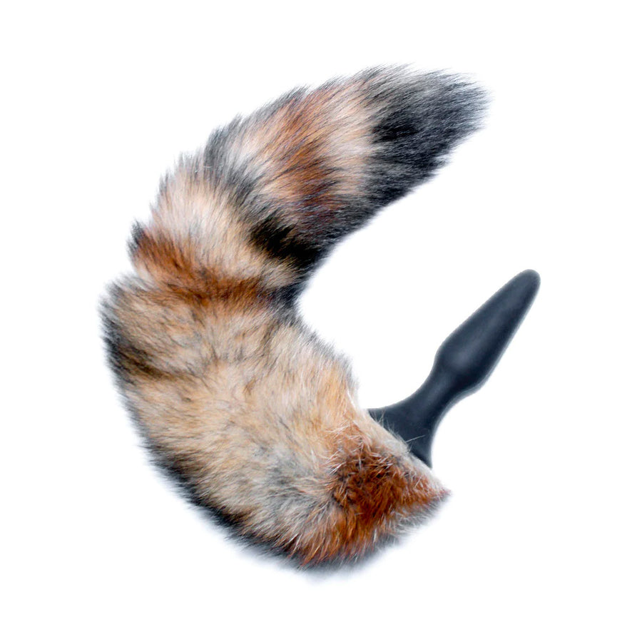 The Fox Tail Silicone Butt Plug is displayed against a blank background. The plug is thin and tapered and made of black silicone. Its wide base is attached to a puffy multi-colored tail made of beige fur with black and brown stripes.