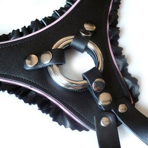 A closeup of the front piece of the La Femme Strapon Harness is shown against a blank background. The pink lining on the harness is made from a zipper.