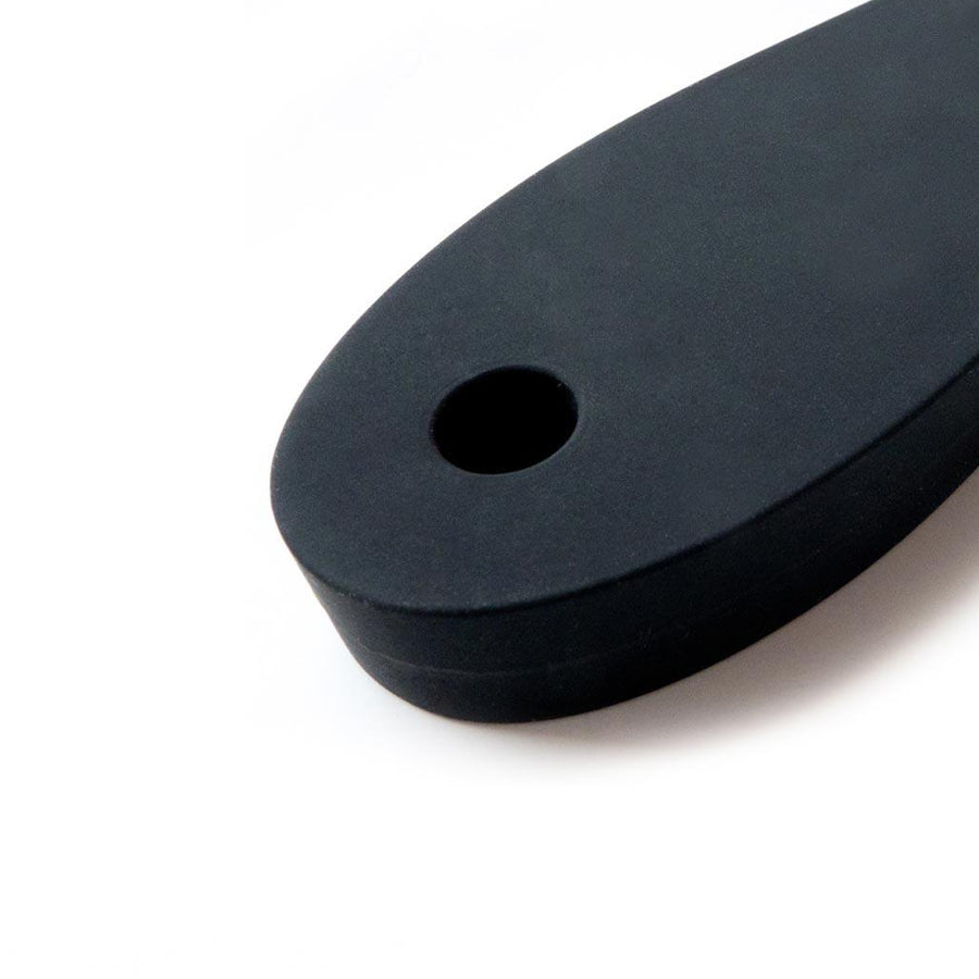 A close-up of the handle of the Tantus Pelt Paddle is shown against a blank background, showing a hole at the base of the handle.