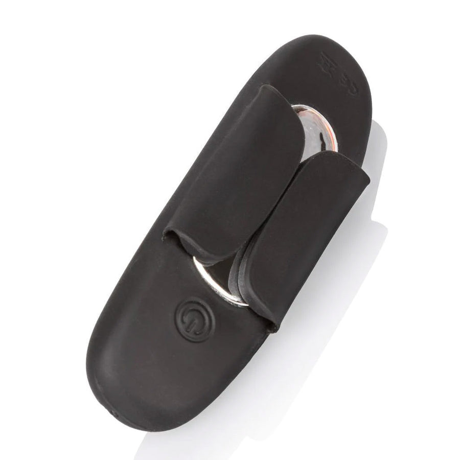 The back of the vibrator from the Lock-N-Play Remote Petite Panty Teaser is shown against a blank background. It has a power button and a metal piece in the center. Two wing pieces made of black silicone on the sides are folded over it.